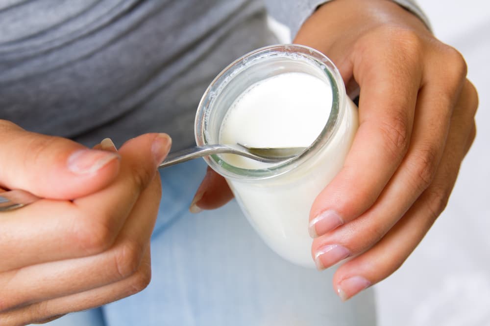 girl picks up yogurt with a spoon