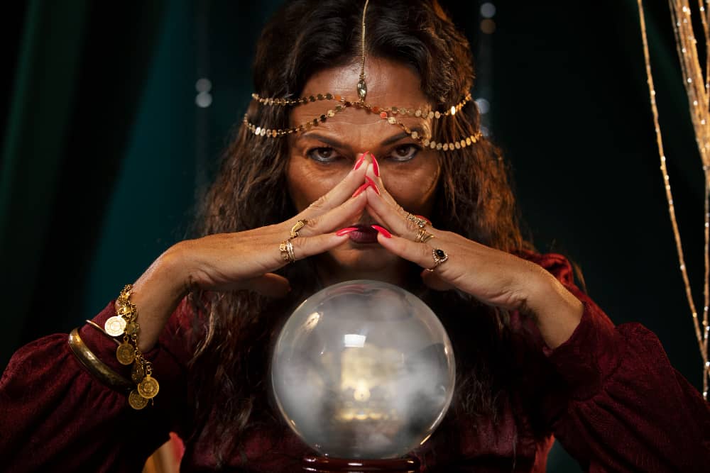 magician with crossed hands over crystal ball