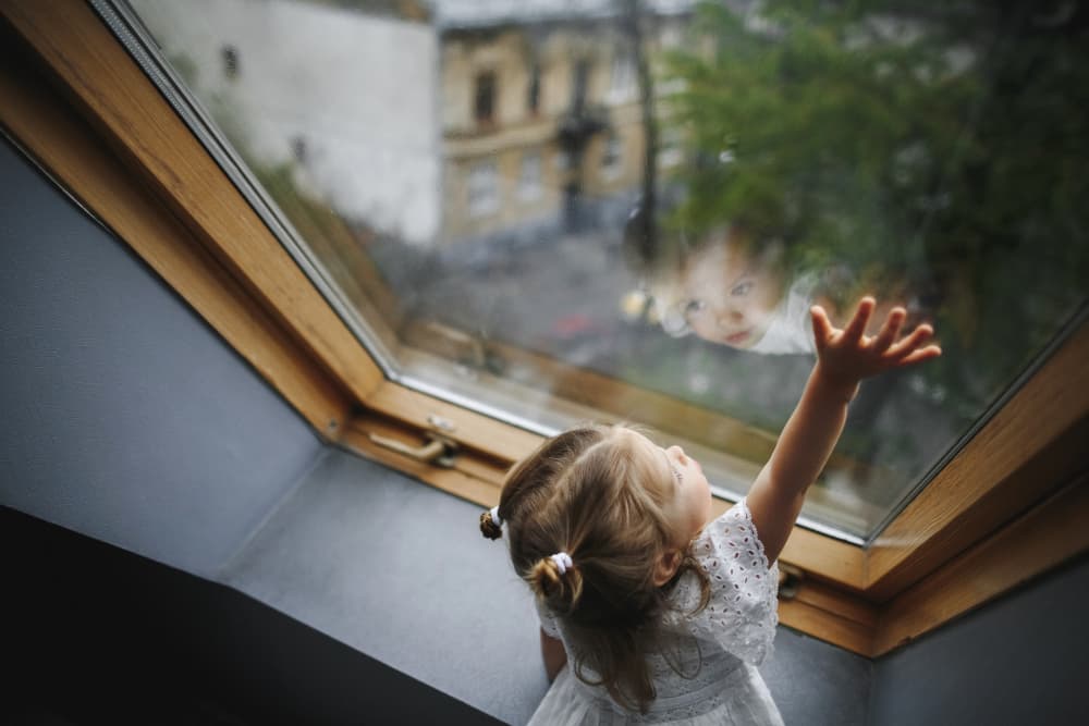 girl stretching arm over window