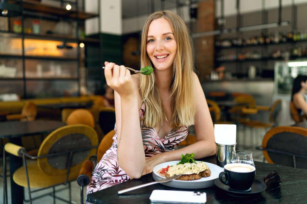 girl eats sitting smiling with spoon towards her mouth