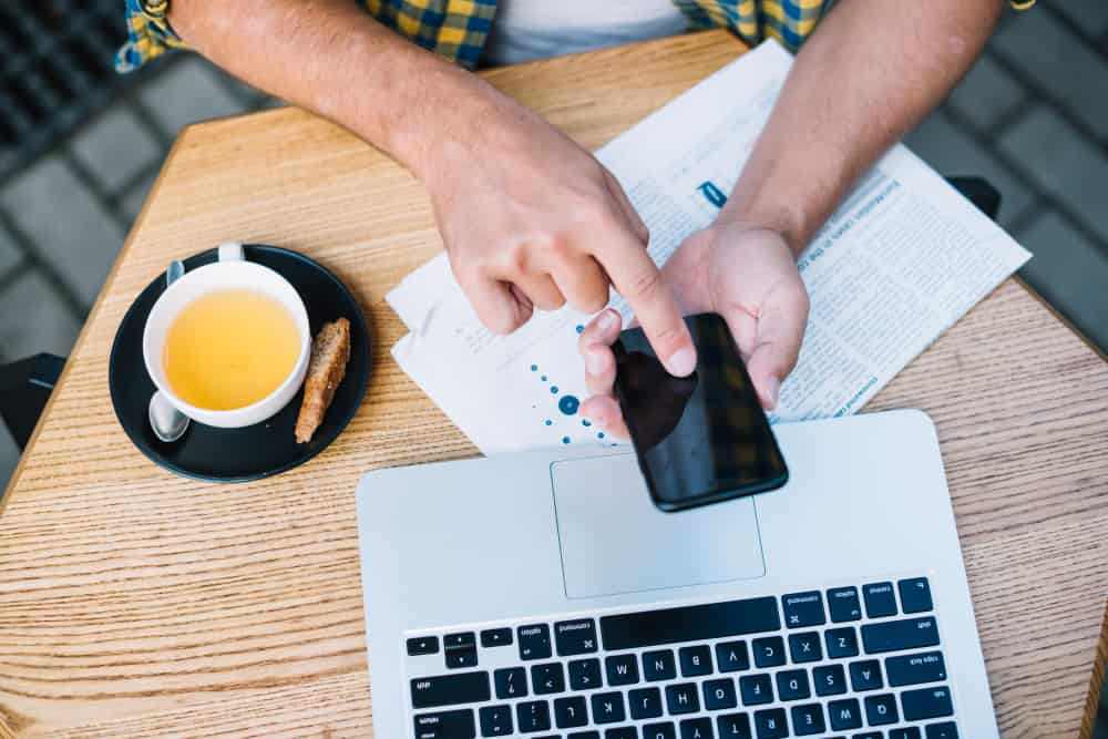 boy with cell phone in front of laptop